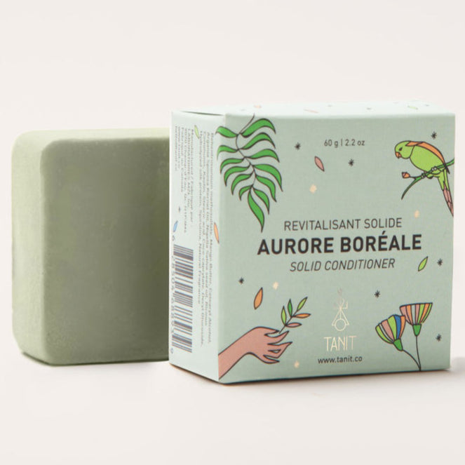 Green bar of soap next to its packaging on a white background