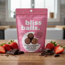 Pink packaging of bliss balls with chocolate and cookie ingredients on a green background