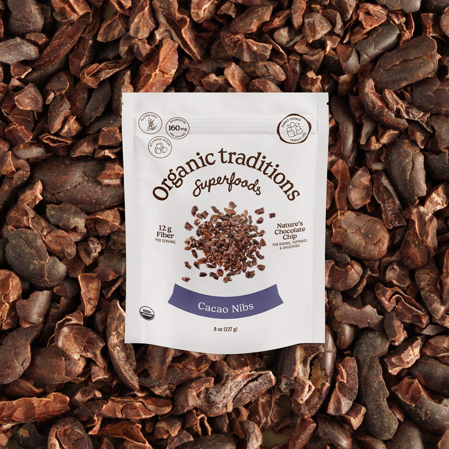 Cacao nibs package on a bed of cacao nibs with 'Organic Traditions Superfoods' branding.