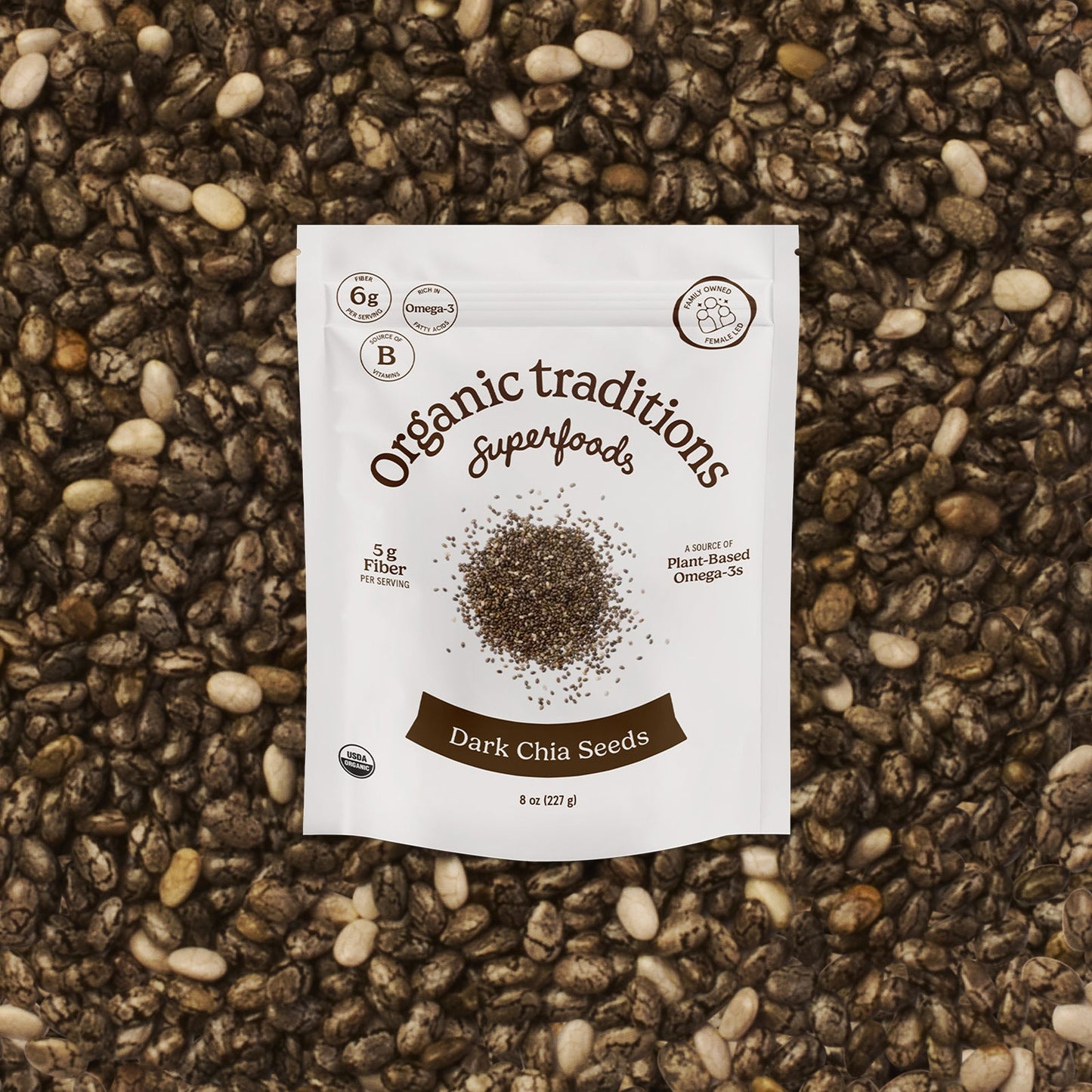 Package of Organic Traditions Dark Chia Seeds on a textured surface with seeds.