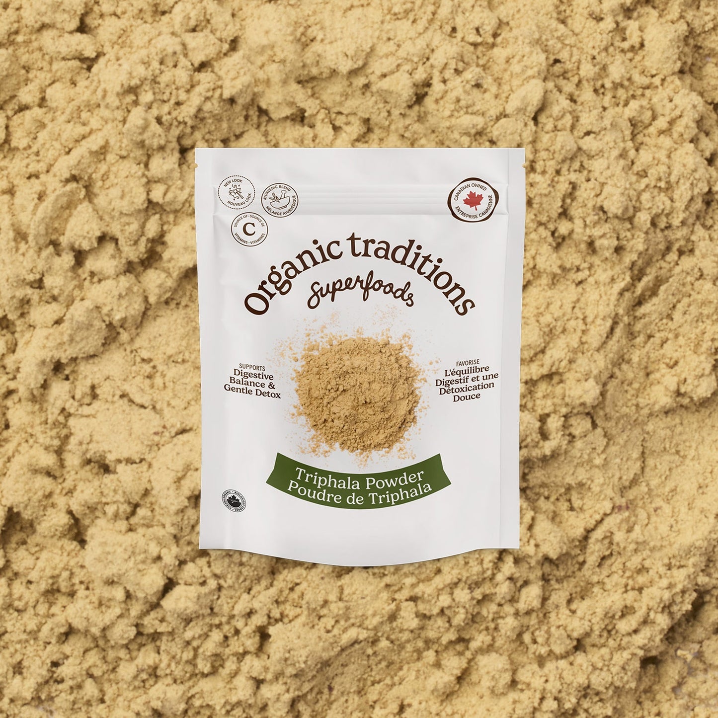 Package of Organic Traditions Triphala Powder on a bed of the powder