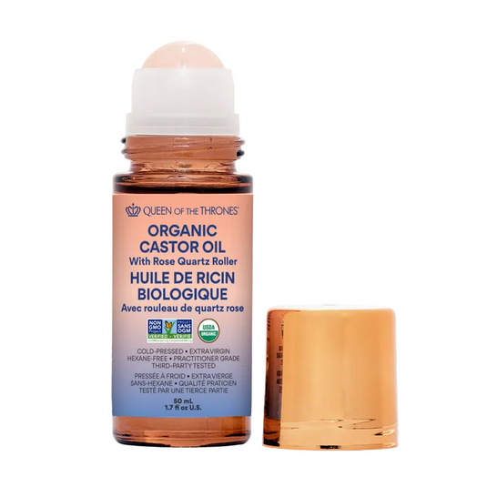 Organic castor oil bottle with rose quartz roller on a gray background