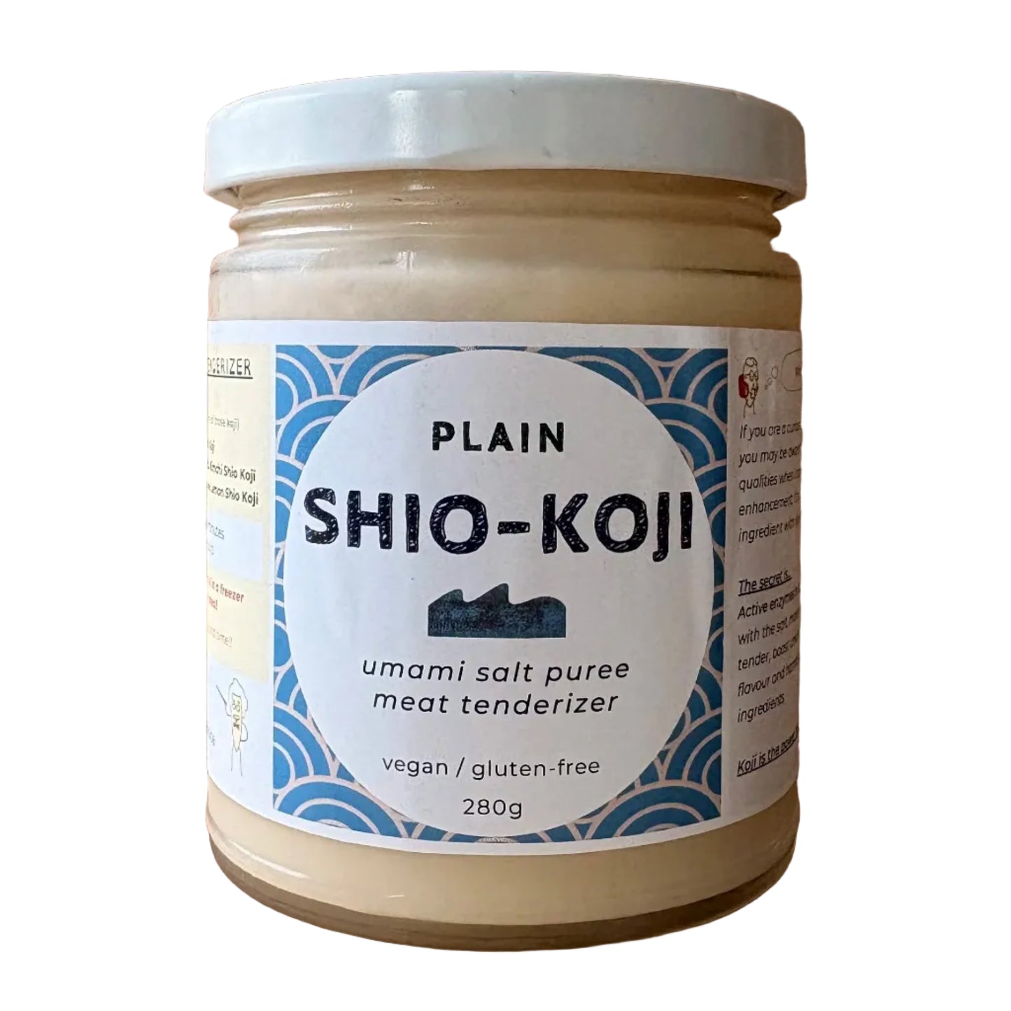 A jar of Plain Shio-Koji umami salt puree meat tenderizer, featuring a white lid and a blue and white label, set on a light wood plank surface.